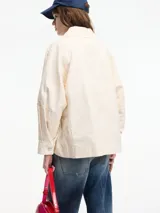 Chaqueta color crema con bordados florales y apliques de pedrería. Tiene cuello camisero, cierre frontal con botones, bolsillos laterales y corte recto.
