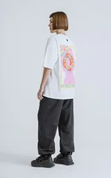 Remera blanca de algodón con estampa sublimada de una figura femenina sosteniendo un salvavidas con la frase "Chill Bitch Trust Karma" y el texto "The Wheel of Fortune". Corte oversize y cuello redondo.