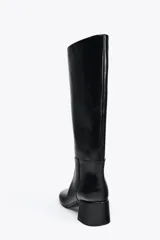 Bota de media caña color negro, de cuero, con punta redonda y tacón ancho.