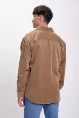 Sobrecamisa de pana color tostado, de corte recto, con cuello camisero, cierre frontal con botones, dos bolsillos de parche en el pecho y mangas largas con puños abotonados.