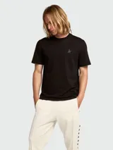 Remera negra de manga corta con cuello redondo y un pequeño logo de estrella en tono negro mate en el pecho.