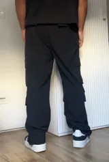 Pantalón cargo negro de corte recto con múltiples bolsillos con solapa y botón a presión.