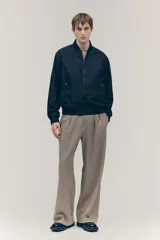 Campera bomber negra liviana con cuello elevado acanalado y cierre delantero. Tiene bolsillos laterales y un bolsillo interior, todos con cierre. Los puños y el bajo son acanalados.