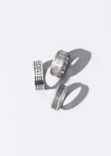 Anillo de acero quirúrgico plateado con diseño labrado de guarda griega en color negro.