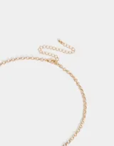 Collar corto dorado con cadena de eslabones y dijes colgantes de corazón, llave, mariposa y camafeo con flores.