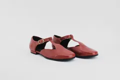 Zapato flat de cuero con estampado de vaca en blanco y negro, con tira delantera y hebilla lateral.