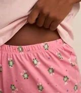 Conjunto de pijama short doll color rosa, compuesto por una remera de manga corta con estampado de texto y un short con estampado de flores.