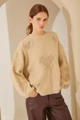 Sweater celeste de punto con cuello redondo y mangas largas abullonadas. Presenta diseño calado con forma de corazones y flores.