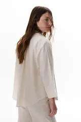 Camisa verde militar de manga larga con puños color crema, cuello clásico y cierre frontal con botones. Tiene un bolsillo en el pecho con bordado de una palmera color crema.