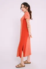 Vestido largo de tejido de punto acanalado color beige claro, con paneles laterales lisos en color marrón. Tiene mangas cortas y cuello redondo.