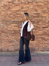 Cartera bandolera de cuero color marrón chocolate, con forro de tela y herrajes dorados. Tiene doble asa de mano y correa larga regulable y desmontable. Incluye bolsillo frontal con cierre y bolsillo interno.