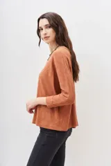 Remera de manga larga color terracota con textura jaspeada, confeccionada en algodón peruano. Presenta un calce holgado con mangas que se ensanchan debajo del brazo y se ajustan en la muñeca.