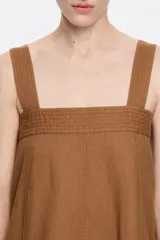 Vestido largo midi de corte línea A, color blanco, confeccionado en mezcla de lino. Presenta escote recto, tirantes anchos, fruncido en la espalda, bolsillos plastrón tipo alforja y pespuntes a contraste en toda la prenda.