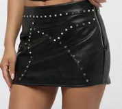 Minifalda negra de cuero sintético con tachas plateadas y cierre lateral con cremallera.