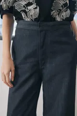 Pantalón de jean azul oscuro, de tiro medio, corte wide leg y bolsillos laterales.