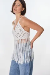 Top blanco de crochet con escote en V, tirantes finos y flecos.