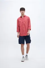 Camisa regular fit de algodón color coral, con cuello solapa clásico, manga larga y bolsillo en el pecho. Cierre frontal con botones personalizados.