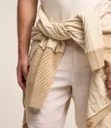 Cardigan de punto beige con diferentes texturas y bloques de color. Tiene cuello en V, abotonadura frontal y mangas largas.