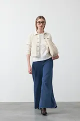 Remera blanca de manga corta con cuello redondo y bordado floral en relieve de color beige claro en el frente.