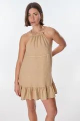 Vestido corto color beige, con escote halter, tirantes finos y falda con volados.