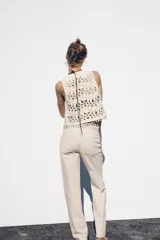 Chaleco abierto de punto color crudo con manga sisa y detalle de conchas en el ruedo.