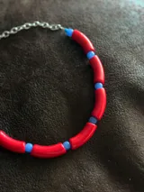 Gargantilla con cuentas de tubo acrílicas rojas y cristales checos azules. Se cierra con cadena de acero quirúrgico y ganchito para regular el largo.