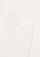 Traje sastrero blanco de tres piezas, compuesto por blazer con solapas de muesca y cierre de un botón, chaleco con escote cuadrado y doble botonadura, y pantalón de corte recto y bota ancha.