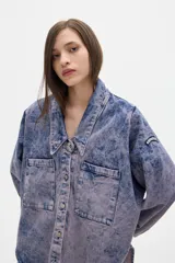 Camisa de jean oversized con lavado washed. Escote en V bajo con cuello camisero, mangas abullonadas.