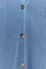 Chaqueta celeste de punto con escote en pico, manga larga y cierre frontal con botones.
