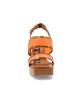 Sandalias de plataforma color naranja con detalles en marrón. Tienen tiras anchas sobre el empeine y el tobillo, y un tacón cuadrado alto.