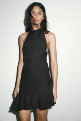 Vestido corto marrón con cuello halter que se ata al cuello, detalle de frunces en la falda y volados asimétricos en el ruedo.