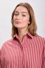Camisa a rayas verticales rojas y blancas, de corte holgado y mangas largas con puños abotonados.
