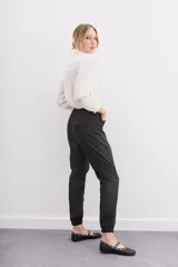 Pantalón babucha negro de lyocell satinado, con elástico en la botamanga, bolsillos plaqué con remaches metálicos y bolsillos cargo en las piernas.