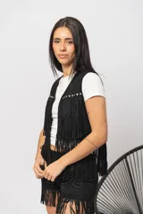 Chaleco negro de gamuza sintética con flecos y tachas plateadas.
