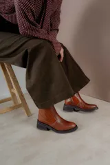 Botas color marrón con textura tipo cocodrilo y tacón bajo, diseño moderno y cómodo.