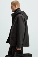 Parka negra de tejido técnico acolchado, corte regular fit, cuello alto con capucha ajustable, manga larga con puños ajustables, bolsillos de solapa en la cadera y bolsillo interior. Cierre frontal con cremallera oculta y botones a presión.
