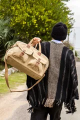 Ruana negra con diseño de rayas verticales en color beige y flecos en el borde inferior.