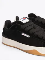 Zapatillas urbanas Tommy Jeans de corte bajo, color negro, confeccionadas en ante con interior de poliéster, entresuela texturizada color crema y suela de goma color caramelo. Presentan logo de la marca en el lateral y en la lengüeta.