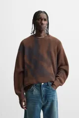 Sweater marrón de punto con cuello redondo y manga larga. Tiene un estampado irregular con efecto spray en color azul.