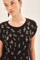 Remera negra de viscosa con calce suelto, escote redondo, manga corta y estampado frontal con bordado de lentejuelas doradas.