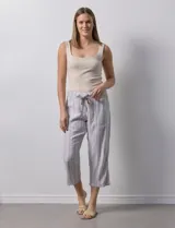 Pantalón capri de lino a rayas verticales en tonos grisáceos y beige, con cintura elástica y lazo ajustable.