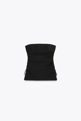 Top negro strapless de tejido fluido con frunces ajustables con cordones en los laterales y aberturas laterales en el ruedo.
