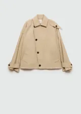 Abrigo color beige con cierre delantero con botones cruzados, cuello camisero, manga larga con trabillas, diseño corto y recto, dos bolsillos laterales y forro interior.