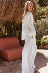Camisa blanca de manga larga con cuello solapa y bordado de flor en el frente.