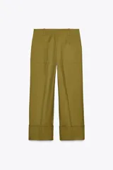 Pantalón color beige de corte ancho, con tiro medio, trabillas en la cintura y raya planchada.