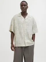 Camisa de manga corta con cuello resort y calce amplio, confeccionada en mezcla de viscosa y lino. Presenta un estampado integral de motivos marinos y botánicos en tonos beige y crema, con cierre frontal de botones.