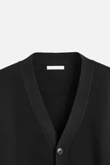 Cárdigan negro de punto de algodón, corte relaxed fit, con cuello en V, manga larga, terminaciones en rib y cierre frontal con botones.