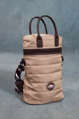 Matera estilo mochila color beige, confeccionada en nylon combinado con símil cuero. Tiene tapa con cierre metálico, bolsillo interno, asas cortas y correa extensible.