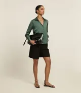 Camisa de satén color verde oliva, de manga larga con puños abotonados y cuello inglés.