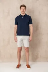 Chomba azul marino de piqué con cuello clásico, tapeta de dos botones y logo de pájaro bordado en color rosa en el pecho.